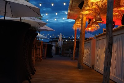 Bar moderne avec éclairage bleu, étagères remplies de bouteilles et ambiance tamisée.