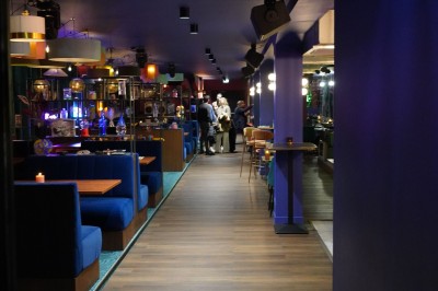 Bar moderne avec éclairage bleu, étagères remplies de bouteilles et ambiance tamisée.