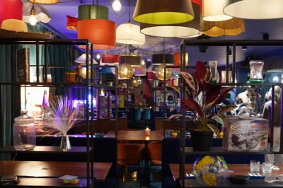 Bar moderne avec éclairage bleu, étagères remplies de bouteilles et ambiance tamisée.