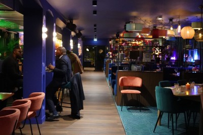 Bar moderne avec éclairage bleu, étagères remplies de bouteilles et ambiance tamisée.