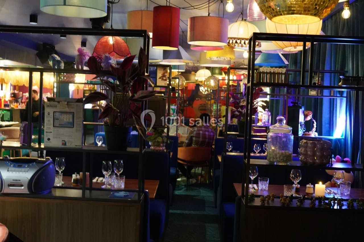 Salle de restaurant colorée avec des tables dressées, des luminaires variés et une ambiance chaleureuse.