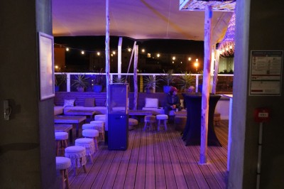 Bar moderne avec éclairage bleu, étagères remplies de bouteilles et ambiance tamisée.