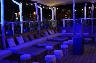 Bar moderne avec éclairage bleu, étagères remplies de bouteilles et ambiance tamisée.