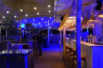 Bar moderne avec éclairage bleu, étagères remplies de bouteilles et ambiance tamisée.