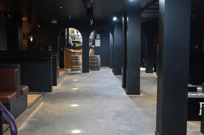 Bar moderne avec éclairage bleu, étagères remplies de bouteilles et ambiance tamisée.