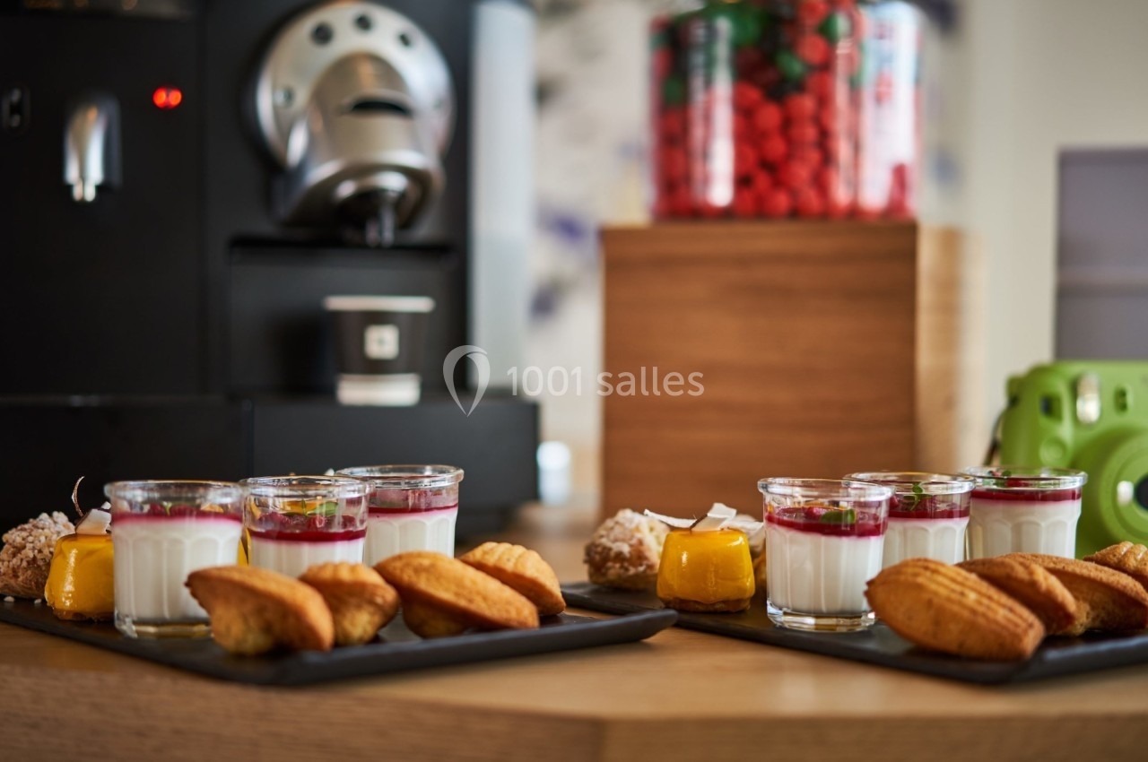 Plateaux de desserts comprenant verrines, madeleines et autres douceurs, disposés près d'une machine à café.