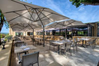Façade d'un château en pierre entouré de végétation, avec un ciel bleu partiellement nuageux en arrière-plan.