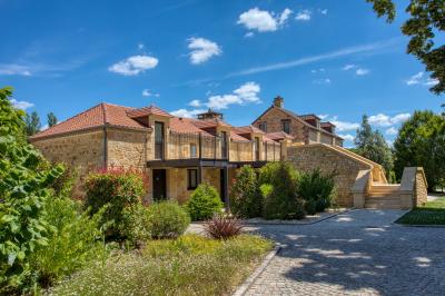Façade d'un château en pierre entouré de végétation, avec un ciel bleu partiellement nuageux en arrière-plan.