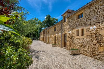 Façade d'un château en pierre entouré de végétation, avec un ciel bleu partiellement nuageux en arrière-plan.