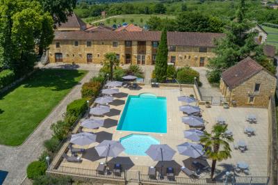 Façade d'un château en pierre entouré de végétation, avec un ciel bleu partiellement nuageux en arrière-plan.