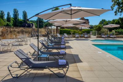 Façade d'un château en pierre entouré de végétation, avec un ciel bleu partiellement nuageux en arrière-plan.