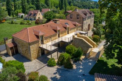 Façade d'un château en pierre entouré de végétation, avec un ciel bleu partiellement nuageux en arrière-plan.