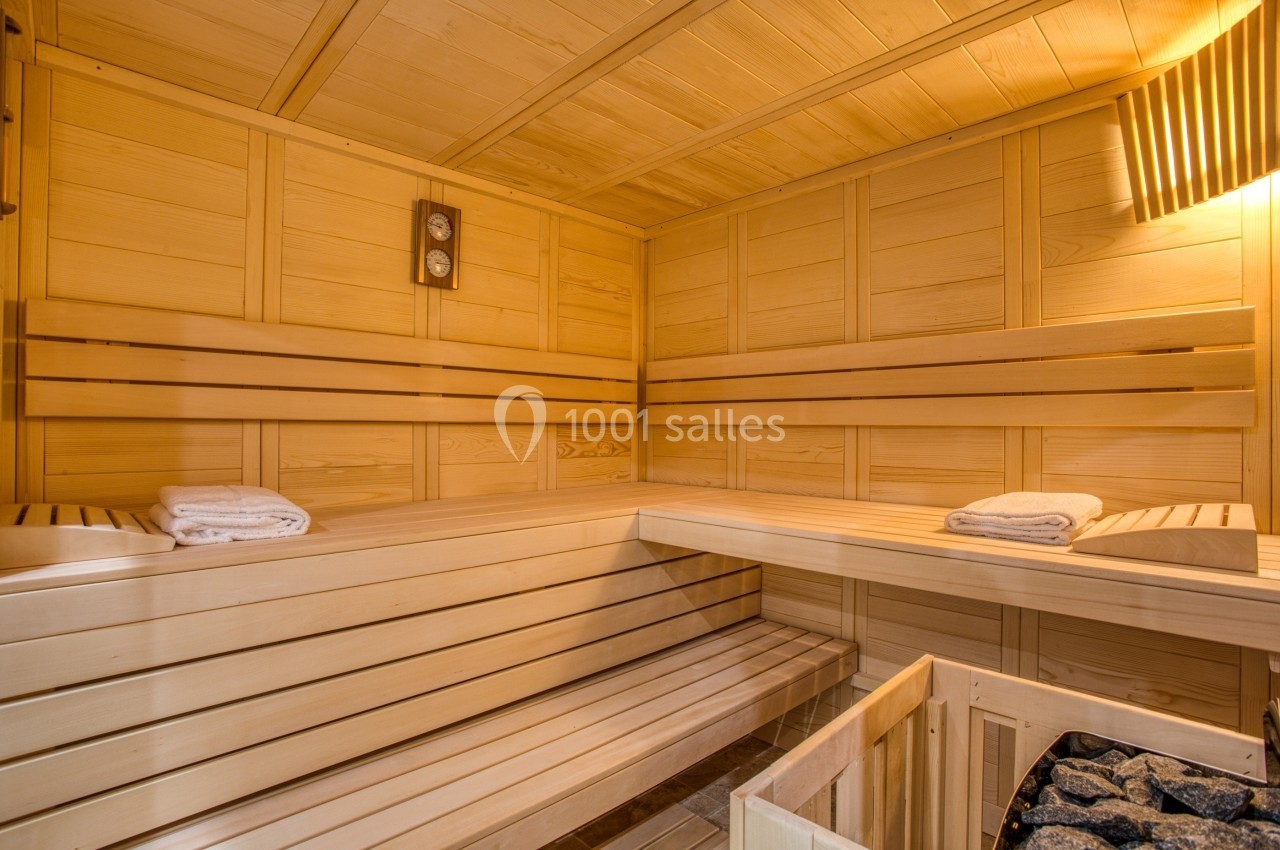 Intérieur d'un sauna en bois clair avec bancs, pierres de chauffage et serviettes pliées.