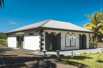 Allée extérieure éclairée la nuit, bordée de végétation et d'un bâtiment blanc avec des marquages au sol.