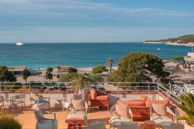 Miniature Location salle Cassis (Bouches-du-Rhône) - Hôtel Liautaud Cassis #3 Salon lumineux avec canapé beige incurvé, chaises en bois, tables basses rondes et plantes en pot près de grandes fenêtres.