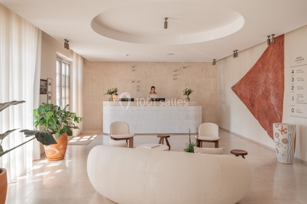 Réception lumineuse avec comptoir moderne, canapé arrondi, plantes en pot et décoration murale contemporaine.