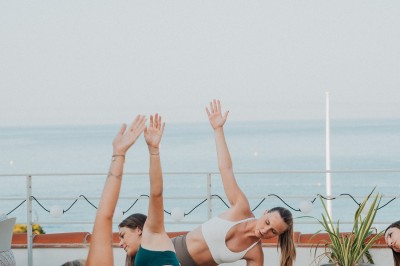 Miniature Location salle Cassis (Bouches-du-Rhône) - Hôtel Liautaud Cassis #4 Salon lumineux avec canapé beige incurvé, chaises en bois, tables basses rondes et plantes en pot près de grandes fenêtres.