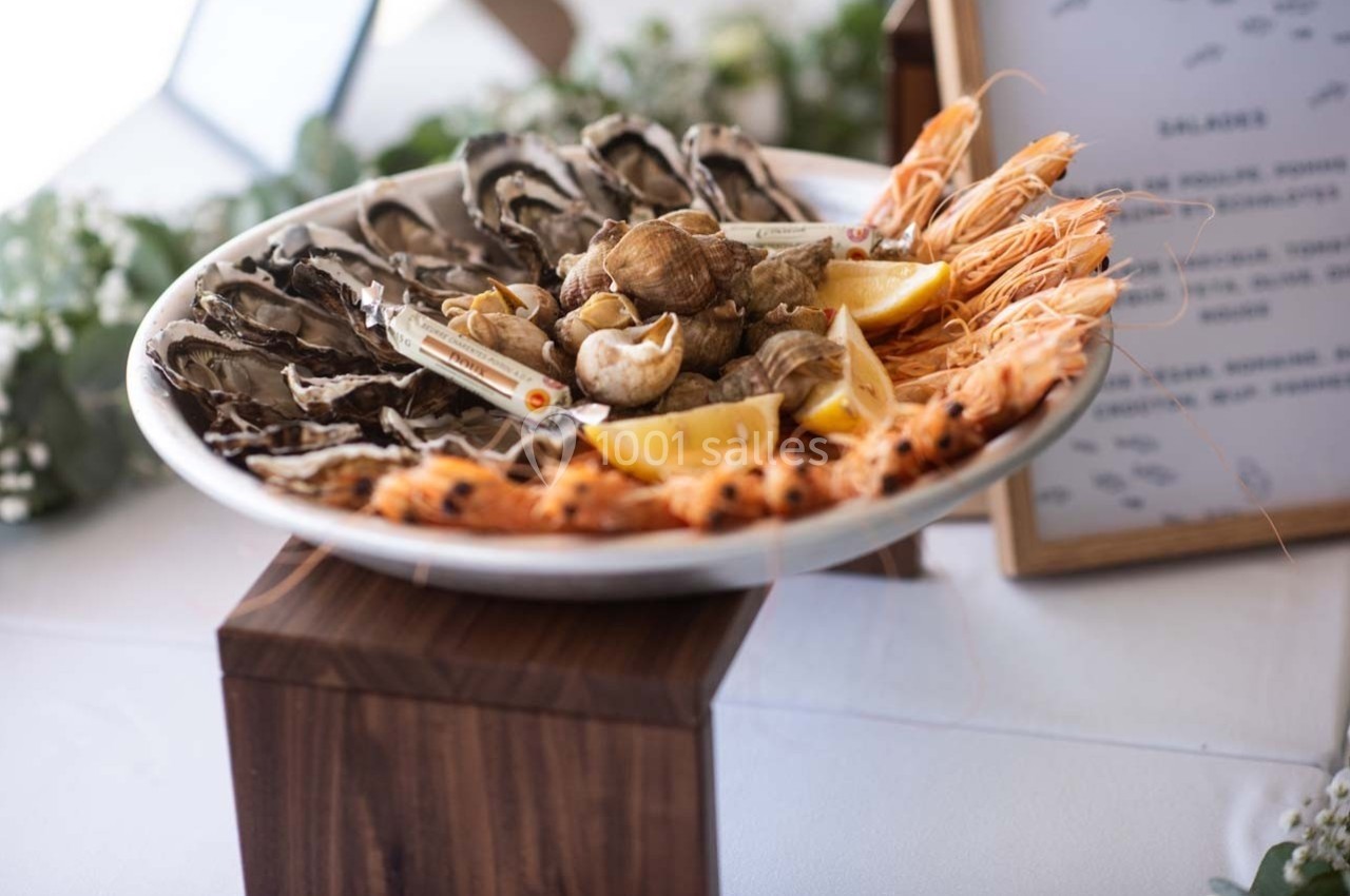 Plateau de fruits de mer avec huîtres, bulots, crevettes et quartiers de citron, présenté sur un support en bois.