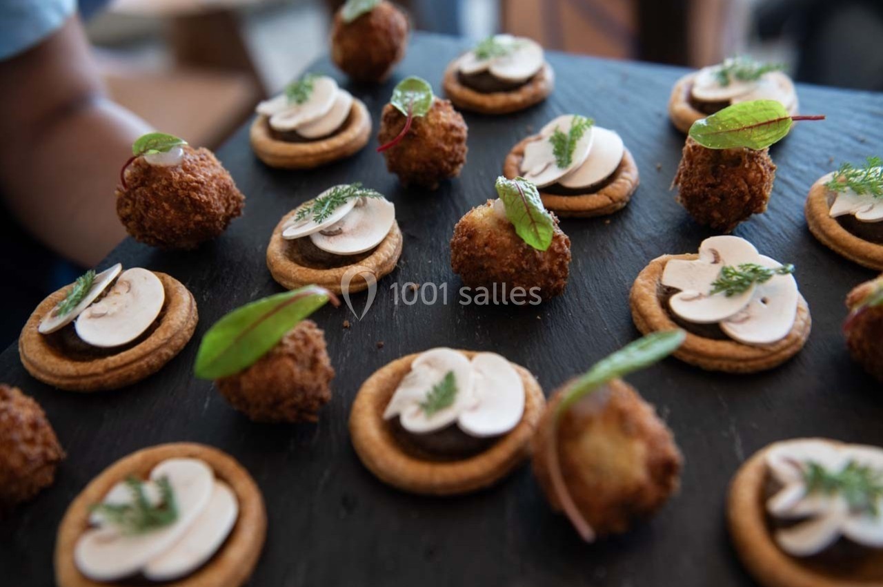 Plateau de bouchées apéritives composées de crackers garnis de champignons et de croquettes dorées avec herbes fraîches.