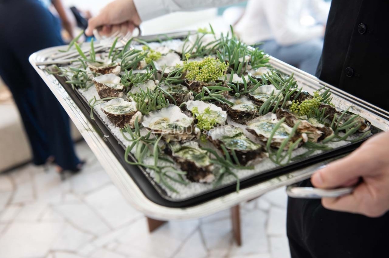 Plateau d'huîtres fraîches garnies de plantes comestibles, présenté sur un lit de glace.