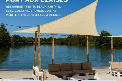 Terrasse d'un restaurant avec voiles d'ombrage, mobilier en bois, vue sur un étang et ambiance estivale.