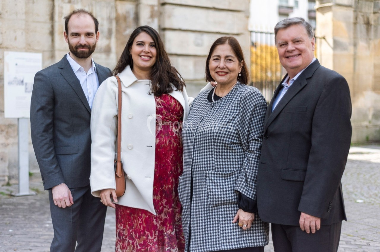 Quatre personnes posant ensemble devant un bâtiment en pierre dans un cadre urbain.