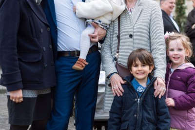 Un couple s'embrasse dans une rue pavée devant un bâtiment rose couvert de végétation.