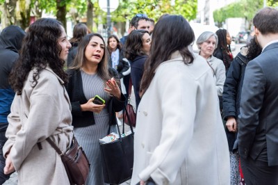 Un couple s'embrasse dans une rue pavée devant un bâtiment rose couvert de végétation.