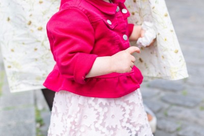 Un couple s'embrasse dans une rue pavée devant un bâtiment rose couvert de végétation.