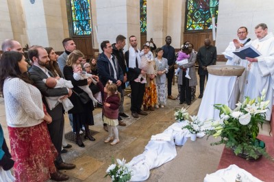 Un couple s'embrasse dans une rue pavée devant un bâtiment rose couvert de végétation.