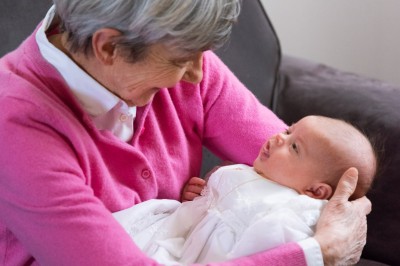 Un couple s'embrasse dans une rue pavée devant un bâtiment rose couvert de végétation.