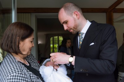Un couple s'embrasse dans une rue pavée devant un bâtiment rose couvert de végétation.