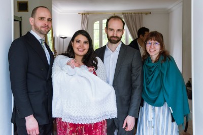 Un couple s'embrasse dans une rue pavée devant un bâtiment rose couvert de végétation.