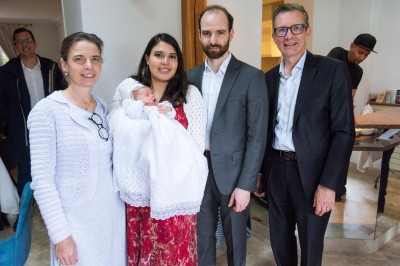 Un couple s'embrasse dans une rue pavée devant un bâtiment rose couvert de végétation.