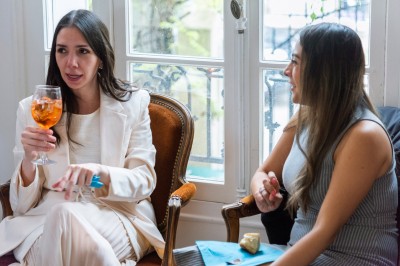 Un couple s'embrasse dans une rue pavée devant un bâtiment rose couvert de végétation.