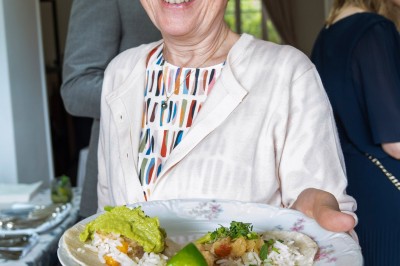Un couple s'embrasse dans une rue pavée devant un bâtiment rose couvert de végétation.