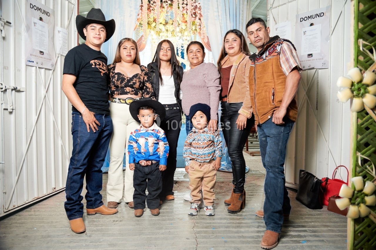 Un groupe de personnes, incluant deux enfants, posant ensemble dans un espace décoré avec des fleurs suspendues.