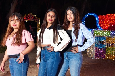 Un groupe de personnes pose devant la tour Eiffel par temps nuageux, dans un espace dégagé bordé d'arbres.