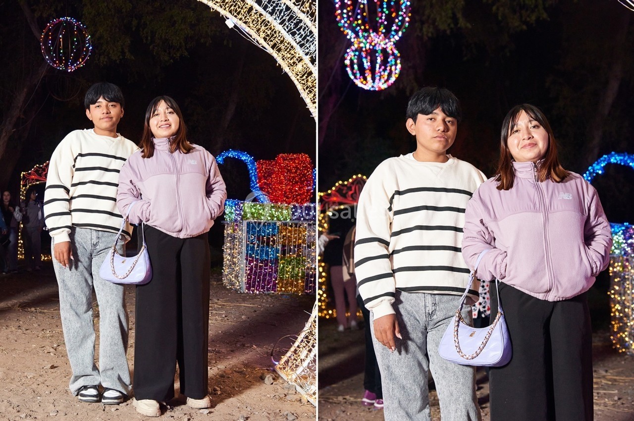 Un couple pose devant des décorations lumineuses colorées dans un cadre nocturne.
