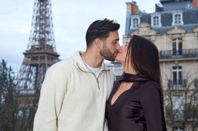 Un groupe de personnes pose devant la tour Eiffel par temps nuageux, dans un espace dégagé bordé d'arbres.