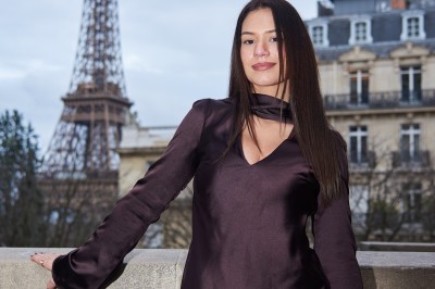 Un groupe de personnes pose devant la tour Eiffel par temps nuageux, dans un espace dégagé bordé d'arbres.