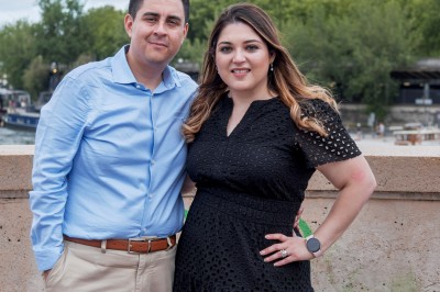 Un groupe de personnes pose devant la tour Eiffel par temps nuageux, dans un espace dégagé bordé d'arbres.