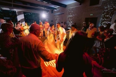Un couple danse au centre d'une piste éclairée par des projecteurs violets et des étincelles, entouré de spectateurs.