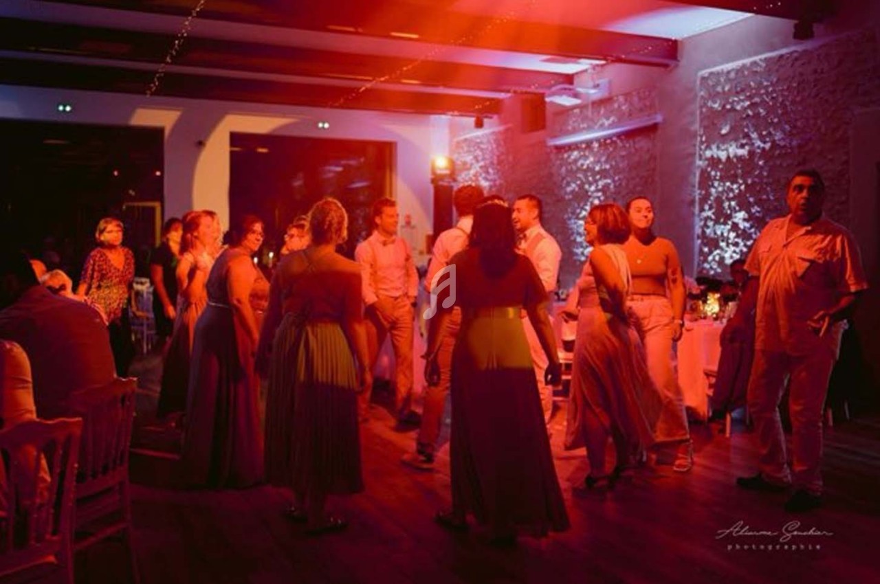 Groupe de personnes dansant dans une salle éclairée par des lumières rouges et tamisées.
