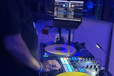 Un DJ mixant de la musique sur une table de mixage avec des vinyles jaunes et un ordinateur portable en arrière-plan.