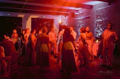 Un couple danse au centre d'une salle éclairée par des projecteurs violets, entouré de jets d'étincelles et de fumée.