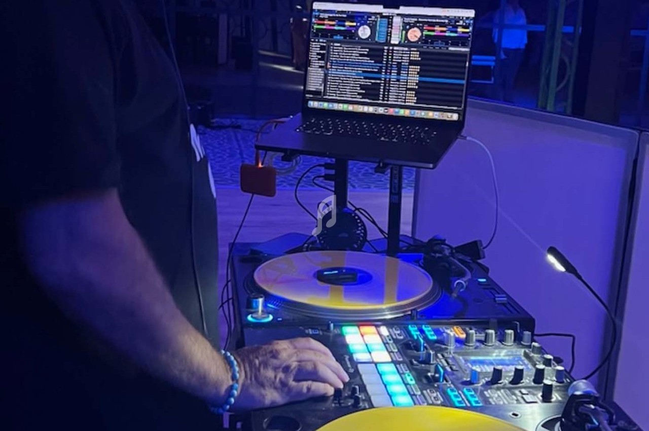 Un DJ mixant de la musique sur une table de mixage avec des vinyles jaunes et un ordinateur portable en arrière-plan.