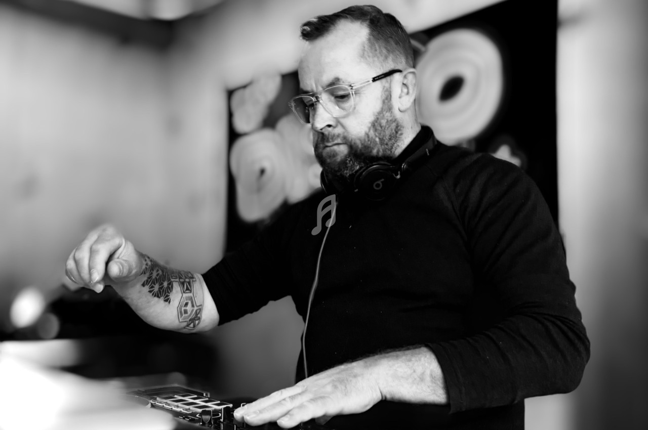Un homme portant un casque audio manipule un équipement de mixage dans un environnement intérieur.