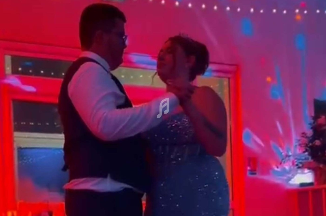 Un couple danse sous un éclairage rouge et bleu dans une salle décorée pour une fête.