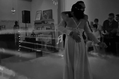 Un couple danse dans une ambiance tamisée avec des effets de lumière et de fumée, entouré de spectateurs.